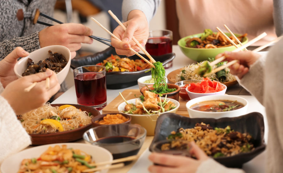 Friends eating tasty Chinese food at table